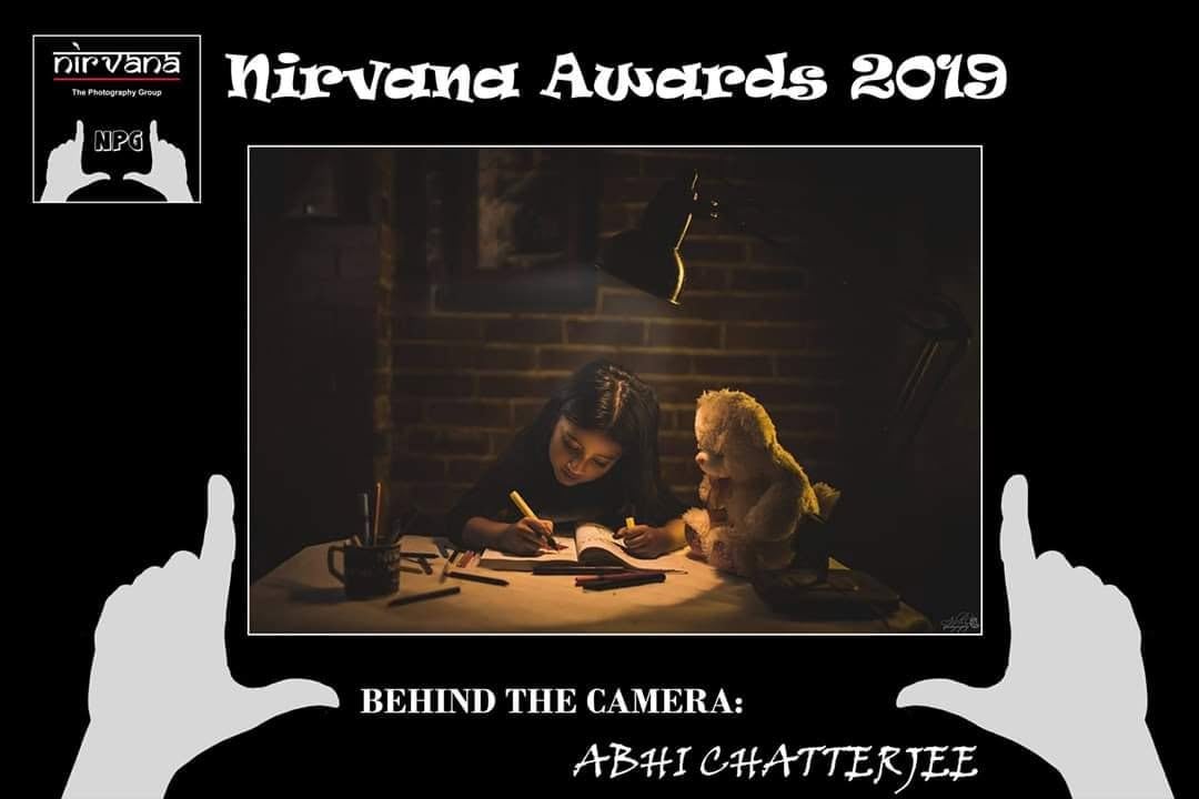 A Nirvana Awards 2019 card holding up a framed picture of a girl writing beside a teddy bear.